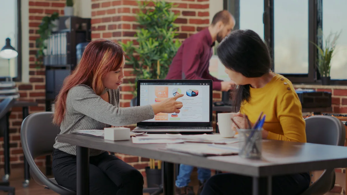 Two colleagues review a laptop dashboard together